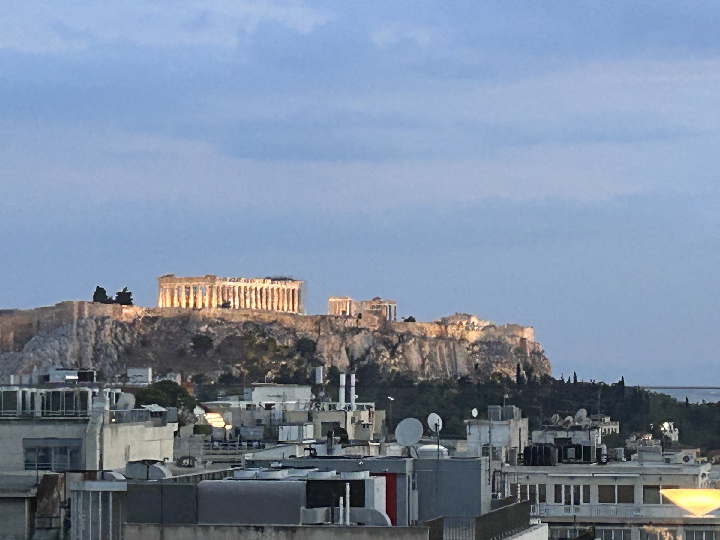 The illuminated Acropolis seen across the Athens rooftops at dusk