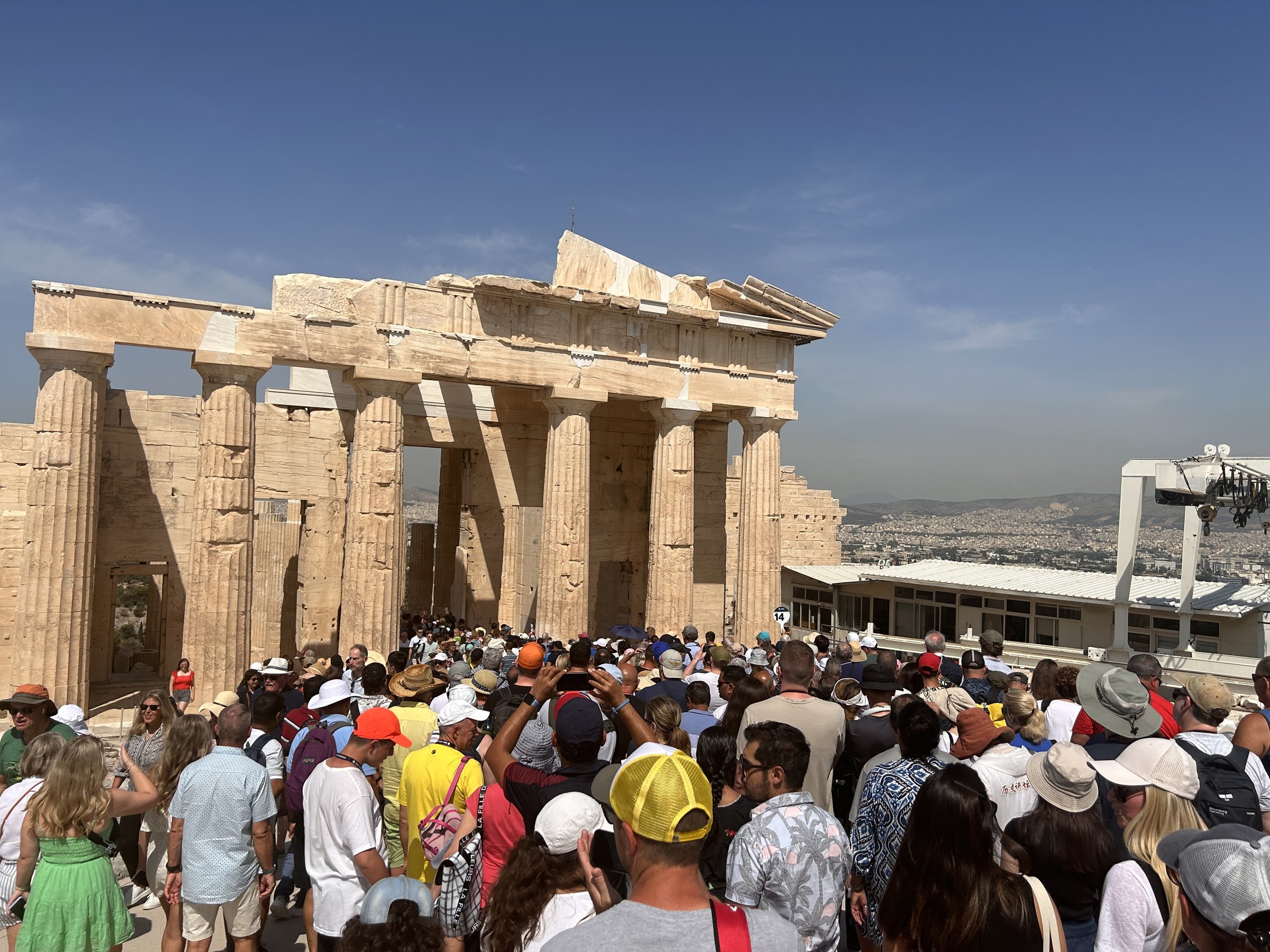 Large June crowds moving through the monumental entrance to the Acropolis