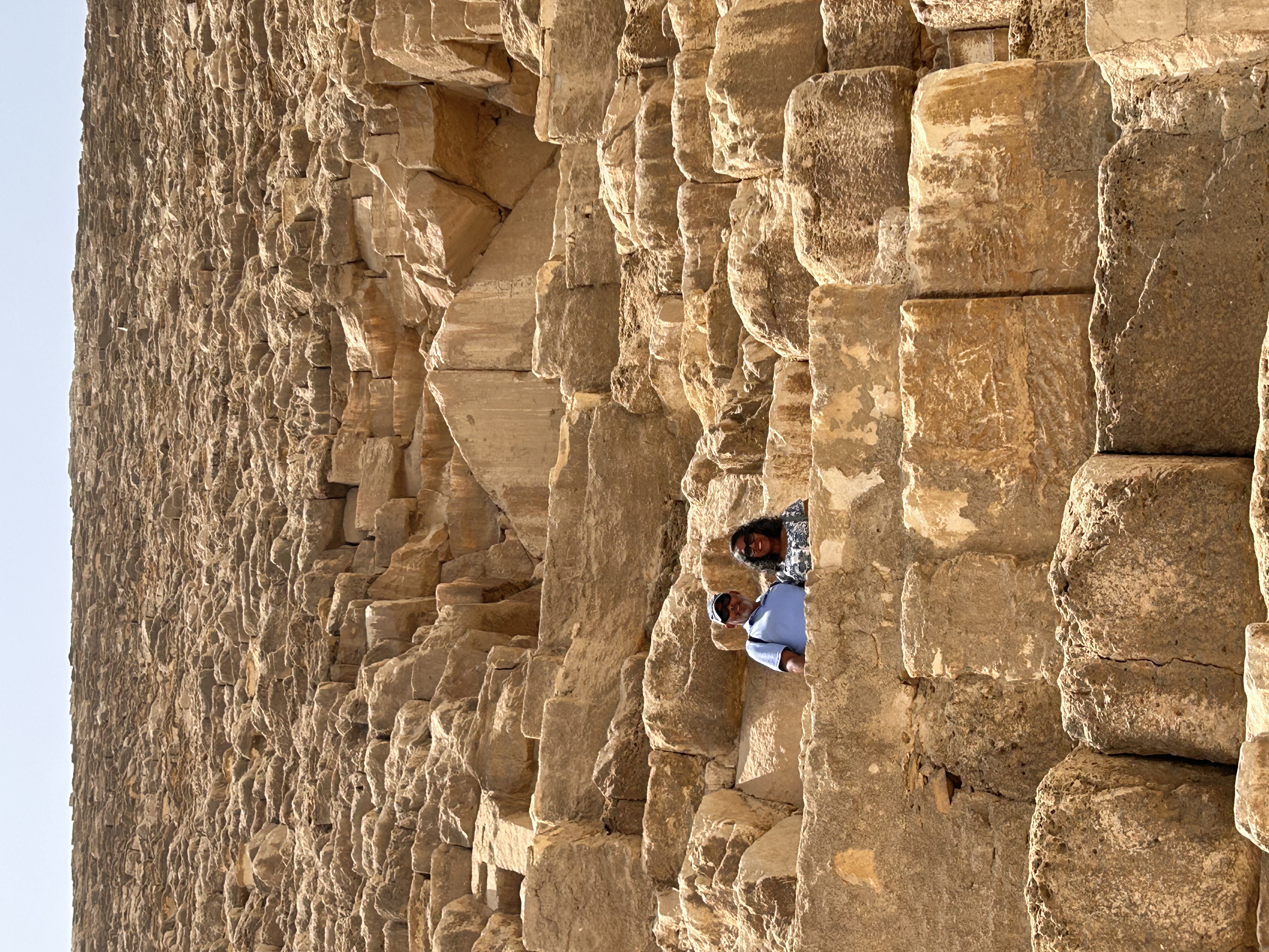 Hiram and Marlene standing among the enormous weathered stones of a pyramid at Giza
