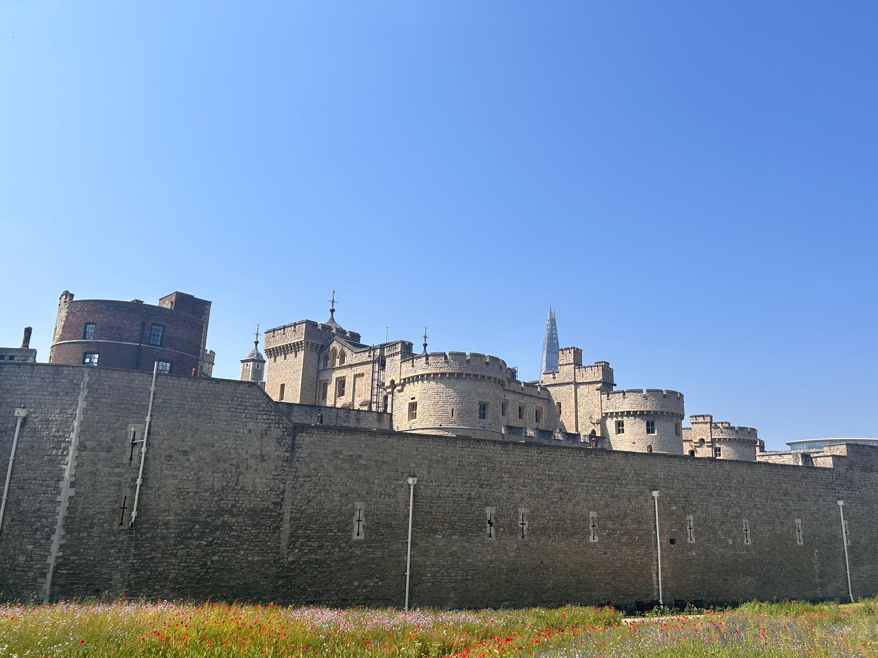 The stone walls and towers of the Tower of London beneath a clear sky
